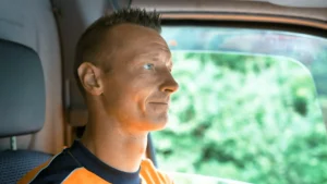 Morten i orange trøje på vej til opgave i sin firmabil